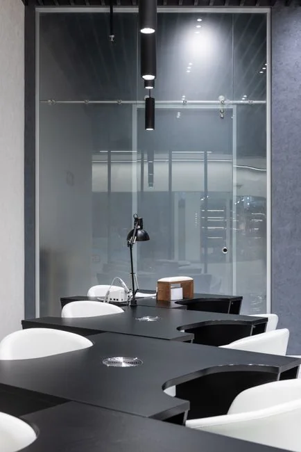 why-choose-us Trois laveurs de vitres, suspendus à des cordes, nettoient en journée la façade d’un immeuble moderne en verre.